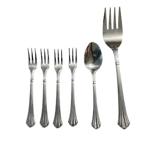 May include: A collection of silver-colored flatware, including six forks and one spoon. The forks have three tines and a decorative handle. The spoon has a rounded bowl and a similar handle design. The flatware is arranged on a white background.