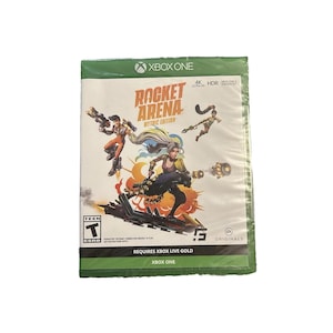 May include: A sealed Xbox One video game case. The game is titled "Rocket Arena" with "Mythic Edition" below. The cover art shows action figures with weapons and explosions. The case is wrapped in clear plastic.
