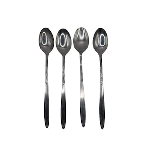 May include: Four stainless steel spoons with oval bowls and long, decorative handles. The spoons are arranged in a row against a white background. The spoons are a shiny silver color.