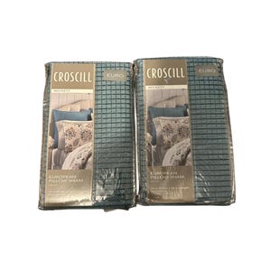 May include: Two packages of Euro European Pillow Shams by Croscill. The pillow shams are in a teal grid pattern. The packaging shows a pillow with a floral design and the text "Beckett". Each sham is 26 inches in width and 26 inches in length.
