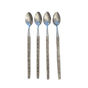 May include: A set of four silver-toned metal spoons featuring long, slender handles with a repeating embossed floral pattern of roses and leaves. Each spoon has a smooth, polished oval bowl and a straight, textured handle design.