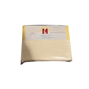 May include: A packaged set of custom fitted sofa bed sheets. The packaging has a cream-colored sheet visible through the clear plastic. The top of the package has a yellow border and text that reads "Hickory at Home" and "Custom Fitted Sofa Bed Sheets".