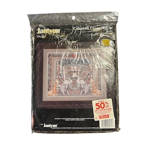 May include: A sealed package containing a counted cross-stitch kit. The kit features a framed design with elephants, giraffes, and a central structure. The package includes the text "Counted Cross Stitch" and a "50% off" sticker.