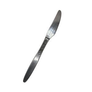 Könnte beinhalten: Ein Edelstahl-Buttermesser mit gezahnter Kante und einem dekorativen Blattmuster am Griff. Das Messer ist abgewinkelt und zeigt die Klinge und den Griff vor weißem Hintergrund. Dieses Utensil ist für Tischgedecke geeignet.