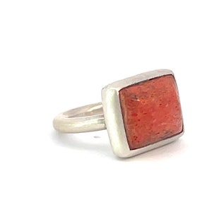 Könnte beinhalten: Ein silberner Ring mit einem quadratischen roten Korallenstein.