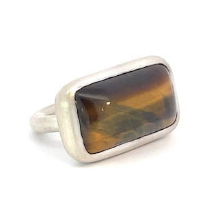 Könnte beinhalten: Ein silberner Ring mit einem rechteckigen braunen Tigerauge-Edelstein.