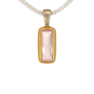 Könnte beinhalten: Eine silberne Kettenkette mit einem goldenen Anhänger mit einem rechteckigen rosafarbenen Edelstein.