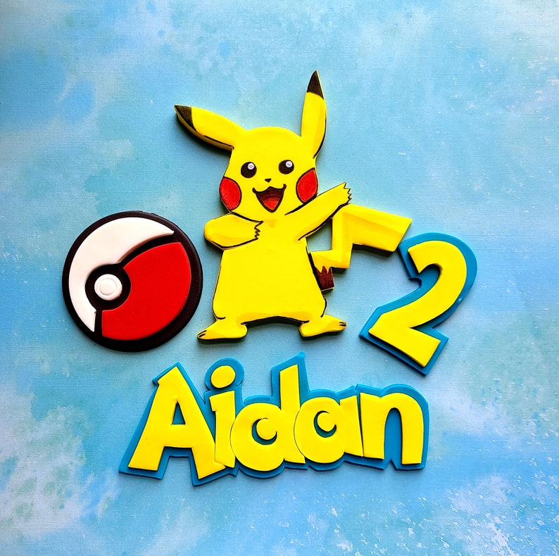 Op de afbeelding: Geel Pikachu-personage met een rode en witte Pok&eacute;bal, een geel nummer 2 en de naam Aidan in gele en blauwe letters.