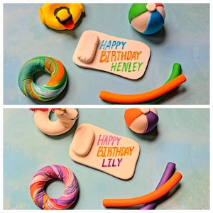 May include: Two cake toppers with the words "Happy Birthday Henley" and "Happy Birthday Lily" on white fondant. The toppers are decorated with colorful fondant shapes, including a pool float, a beach ball, and a pool noodle.