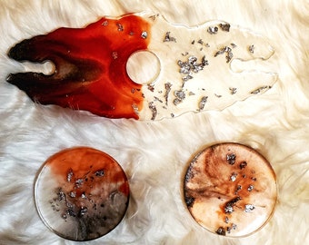 May include: Three resin coasters with a red, white, and brown marbled design. The coasters have a silver glitter finish.