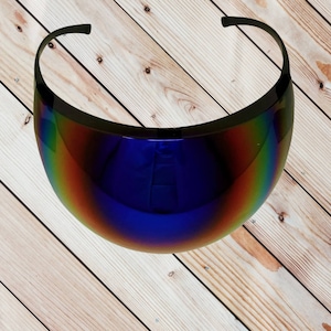 May include: A pair of futuristic, iridescent blue visor sunglasses with a black frame. The sunglasses are on a wooden surface.