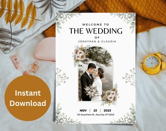 May include: A white wedding invitation with green and white floral illustrations. The invitation features a photo of a couple in a natural setting. The text reads "Welcome to The Wedding of Jonathan & Claudia" and includes the date "Nov 23, 2023" and the address "123 Anywhere St. Any City, ST 12345".