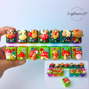 May include: A collection of colorful, whimsical keycaps featuring mushroom and animal designs. Each keycap is adorned with a unique 3D sculpted character, including bears, snails, and mushrooms, set against a green background. The keycaps are arranged in rows, showcasing a variety of vibrant colors.