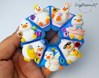 Handgemaakte pillendoos met eendje in een bepaalde pose voor 7 dagen, wekelijkse dispenser voor vitaminesupplementen.