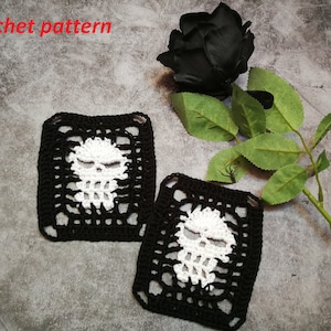 May include: Two square crochet coasters featuring a skull design. The skulls are white, and the coasters have a black border. A black rose and green leaves are in the background. The text "crochet pattern" is in the upper left corner.