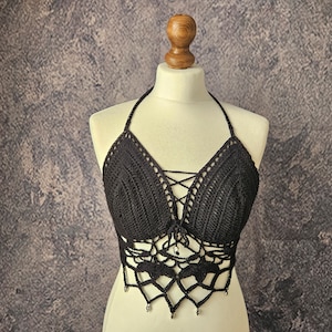 Puede incluir: Un top halter de crochet negro con un frente de encaje y detalles de cuentas.
