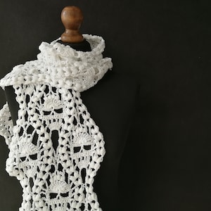 May include: White crocheted scarf with a delicate, lacy pattern. The scarf is draped over a wooden mannequin.