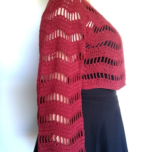 Puede incluir: Un top de crochet rojo con un dise&ntilde;o de encaje y mangas largas.