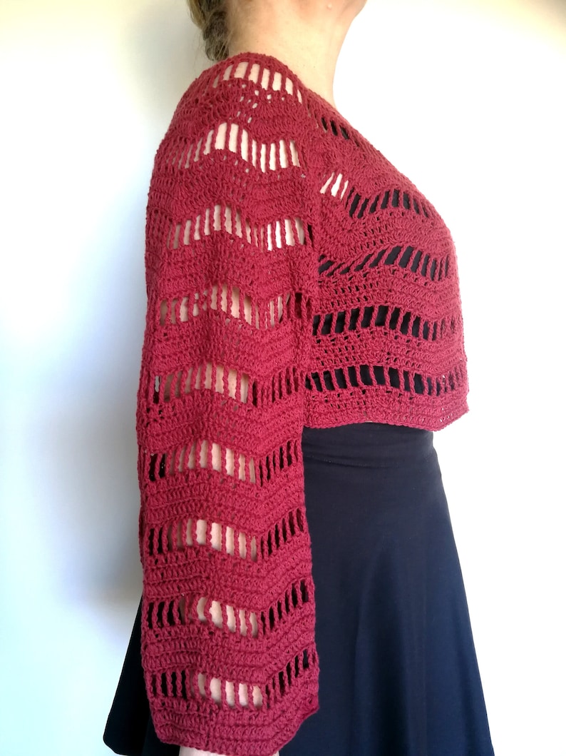 Puede incluir: Un top de crochet rojo con un dise&ntilde;o de encaje y mangas largas.