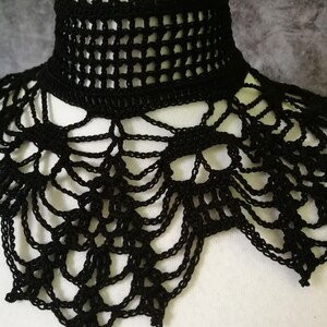 Puede incluir: Un cuello de ganchillo negro con un cuello alto y estructurado y un dise&ntilde;o calado. El cuello se muestra en una cabeza de maniqu&iacute; blanca, destacando sus intrincados detalles y textura. El dise&ntilde;o del cuello presenta una combinaci&oacute;n de patrones geom&eacute;tricos y fluidos.