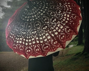 May include: A decorative umbrella with a unique, openwork design. The umbrella's canopy features a gradient of colors, transitioning from a deep red to black. The intricate pattern is set against a white background, creating a striking visual contrast.