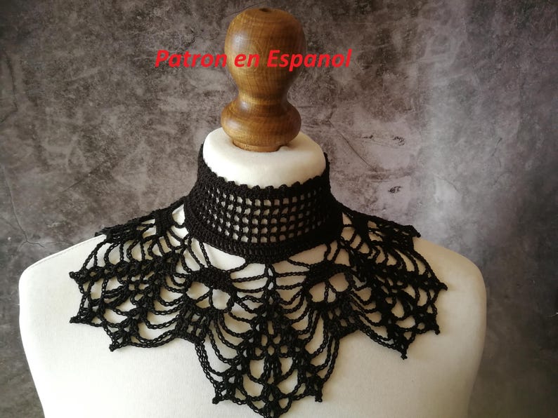 Puede incluir: Cuello negro de ganchillo exhibido en un busto de maniqu&iacute; blanco. El cuello presenta un dise&ntilde;o calado detallado, con un escote tipo gargantilla y un borde inferior decorativo en forma de telara&ntilde;a. El texto "Patron en Espanol" es visible.
