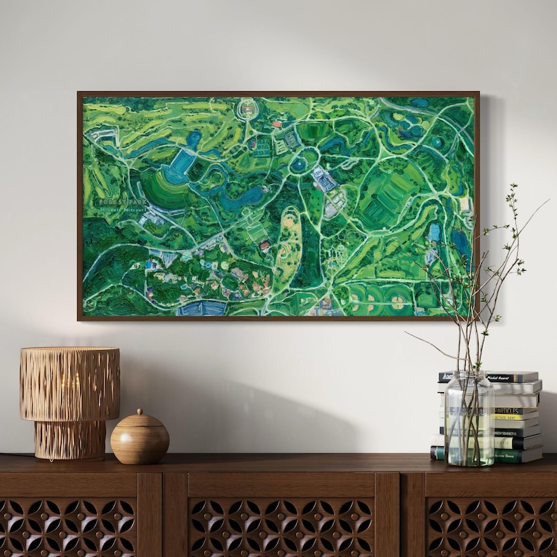 The vibrantly green and colorful Forest Park painting framed on wall in home interior setting above a wooden console with rustic, natural accents.