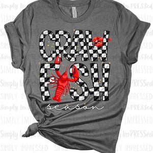 May include: Grey t-shirt with a black and white chequered design that says "Crawfish season" with a red crawfish illustration.