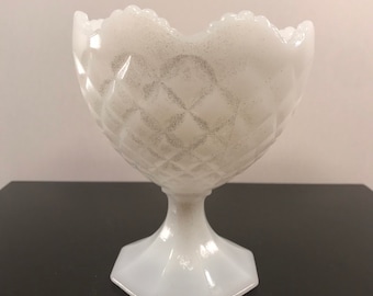 May include: A white milk glass bowl with a diamond pattern and a scalloped rim. The bowl sits on a white pedestal with a hexagonal base.