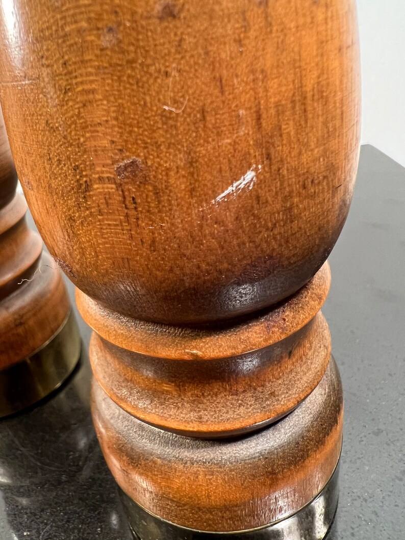 Peut inclure: Deux sali&egrave;res et poivri&egrave;res en bois avec des bases en laiton. Les sali&egrave;res sont brunes et ont une forme ronde et lisse.