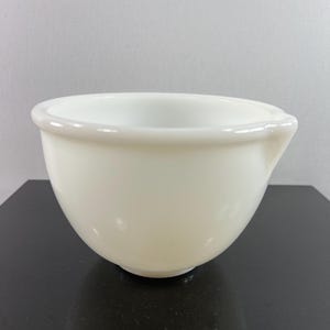 May include: A white ceramic mixing bowl with a slightly flared rim and a small pour spout on the side.