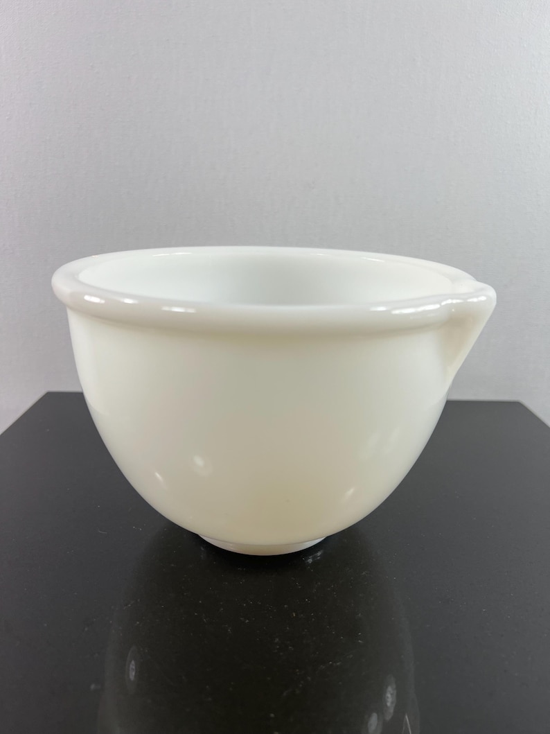 May include: A white ceramic mixing bowl with a slightly flared rim and a small pour spout on the side.