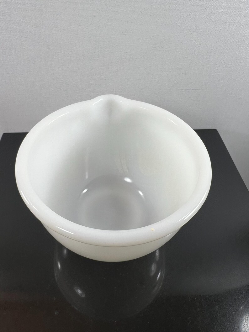 May include: A white ceramic mixing bowl with a pouring spout. The bowl is round and has a smooth, glossy finish.