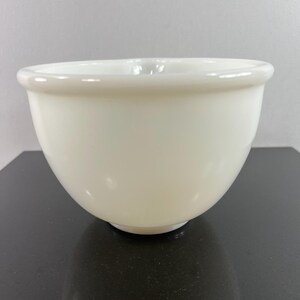 May include: A white ceramic mixing bowl with a smooth, rounded surface. The bowl is empty and appears to be in good condition.