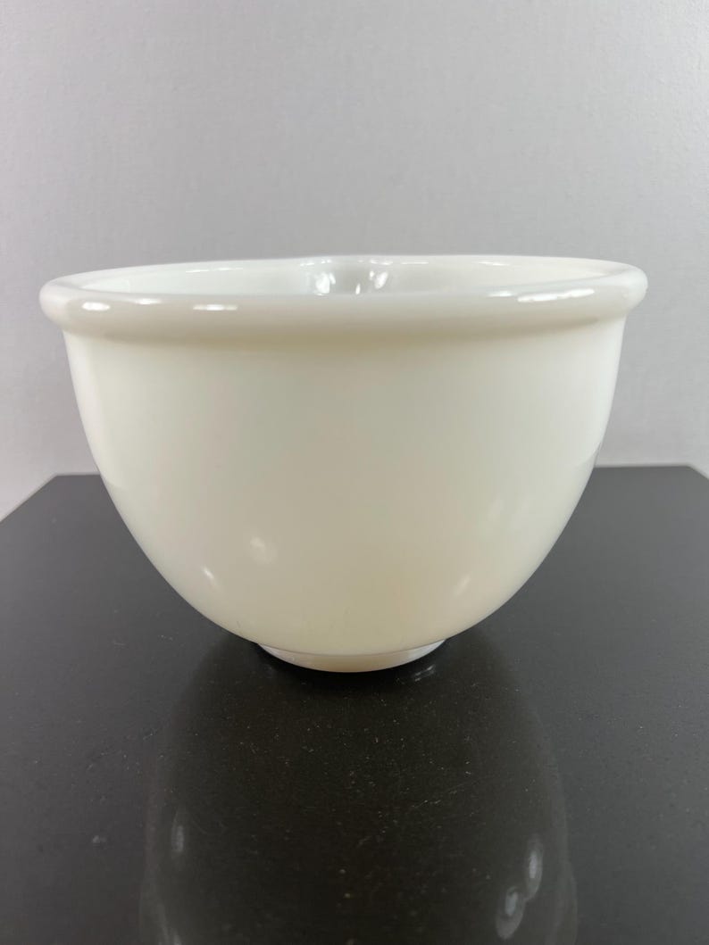 May include: A white ceramic mixing bowl with a smooth, rounded surface. The bowl is empty and appears to be in good condition.