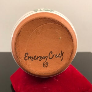 May include: The bottom of a terracotta pottery vase with the words "Emerson Creek" and the number "89" handwritten in black.