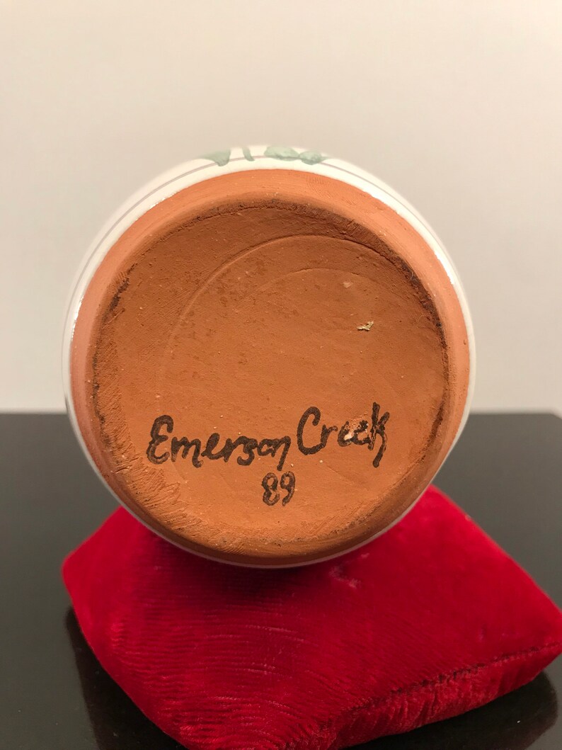 May include: The bottom of a terracotta pottery vase with the words "Emerson Creek" and the number "89" handwritten in black.