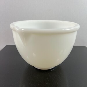 May include: A white ceramic mixing bowl with a smooth, rounded surface. The bowl is empty and appears to be in good condition.