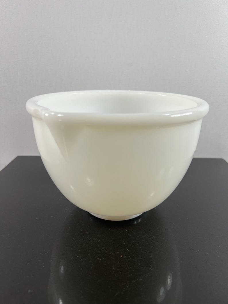 May include: A white ceramic mixing bowl with a smooth, rounded surface. The bowl is empty and appears to be in good condition.