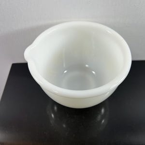 May include: White ceramic mixing bowl with a pouring spout. The bowl is round and has a smooth, glossy finish.