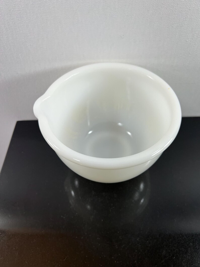 May include: White ceramic mixing bowl with a pouring spout. The bowl is round and has a smooth, glossy finish.