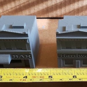 May include: Three gray miniature buildings with white lettering. The buildings are labeled "BAR", "HARDWARE", and "RX Pharmacy".