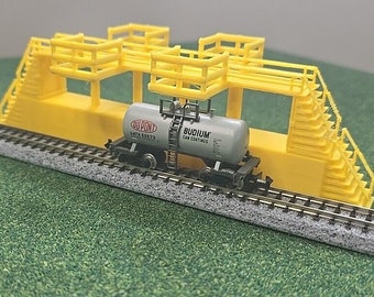 May include: A model train car with a yellow platform and stairs. The car is carrying a gray tank car with the text "DUPONT GATX 62673" and "BUDIUM CAR COATINGS".