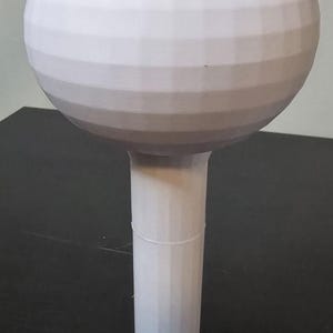May include: A white, 3D printed model of a water tower. The tower has a round top and a cylindrical base.
