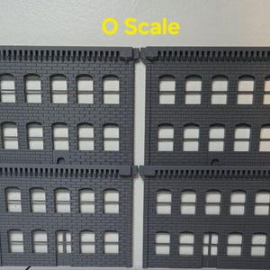 May include: Two gray, three-story brick building facades with windows and a door. The buildings are labeled "O Scale".