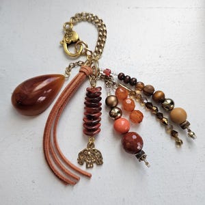 The Savanna Glow Statement Bag Charm combines earthy elegance and serene luxury. Blend of warmth, a touch of strength, spirit and style