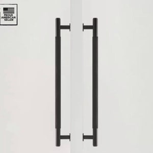 Puede incluir: Dos tiradores de puerta negros con un diseño rectangular. Los tiradores están montados sobre una superficie blanca. La imagen incluye un logotipo de "Proud American Seller" en la esquina superior izquierda.