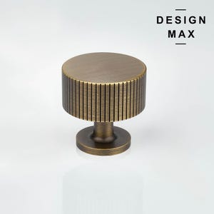 May include: A round, brass cabinet knob with a ribbed design. The knob has a smooth, polished finish.
