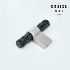 Pode incluir: Botão de armário em forma de T preto e prateado com uma pega preta texturizada. DESIGN MAX está impresso em preto sobre um fundo branco.