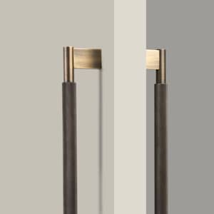 Może przedstawiać: Dwa szczotkowane mosiężne uchwyty do szafek z fakturowanym czarnym wykończeniem. Uchwyty są zamontowane na białej ścianie.